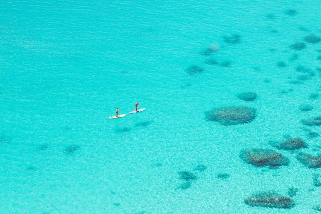 duas pessoas de stand up paddle no mar cristalino da sardenha
